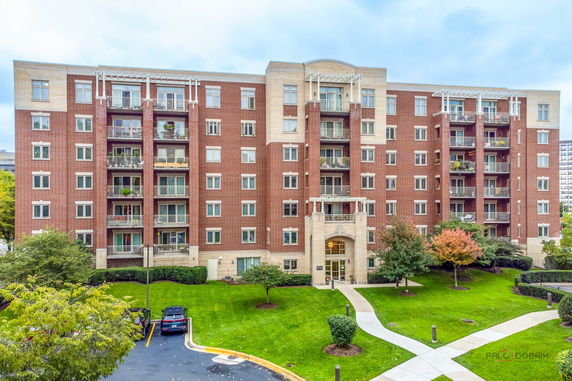 Front view of a multi-story brick apartment building with balconies.