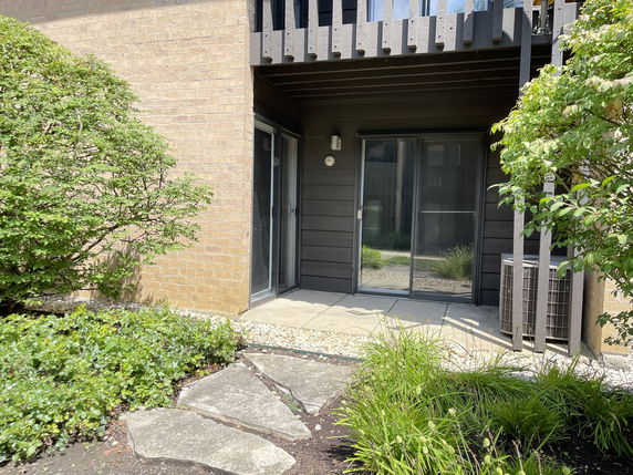 Front view of a building with sliding glass doors and a small patio area.