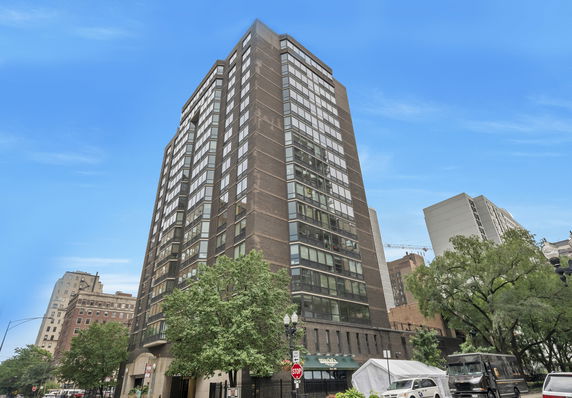 Front view of a tall building with large windows and a brick facade.