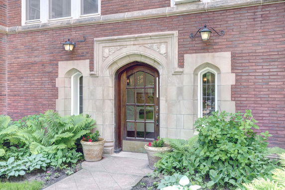 Front view of a brick building with an arched wooden door and decorative stonework.