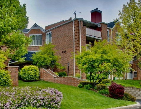 Front view of a multi-story brick residential building with balconies and a chimney.