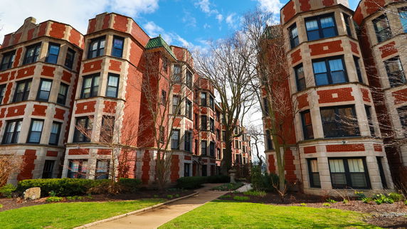 Front view of a multi-story brick building with bay windows.