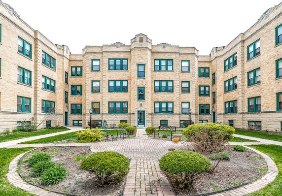 Front view of a multi-story brick apartment building with a courtyard.