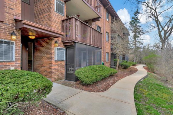 Front view of a multi-story brick apartment building with balconies and a walking path.