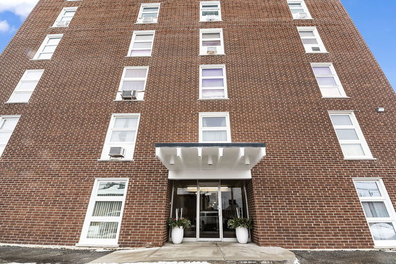 Front view of a multi-story brick building with multiple windows and a glass entrance.