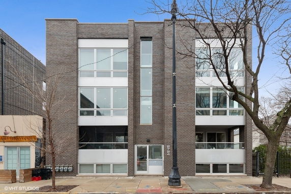 Front view of a three-story brick building with large windows.