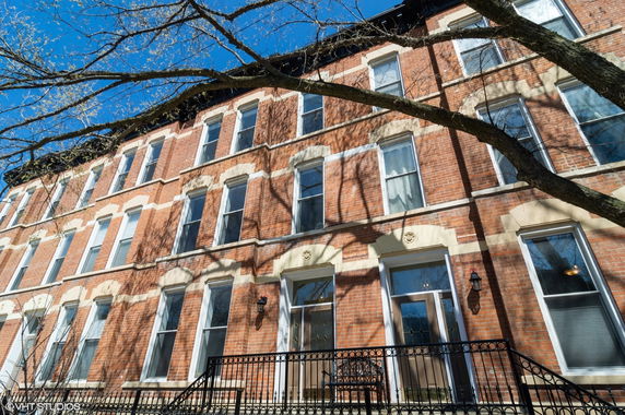 Front view of a multi-story brick building with large windows.
