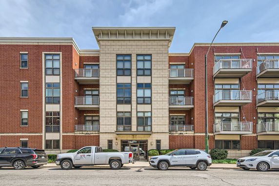 Front view of a multi-story brick apartment building with balconies.