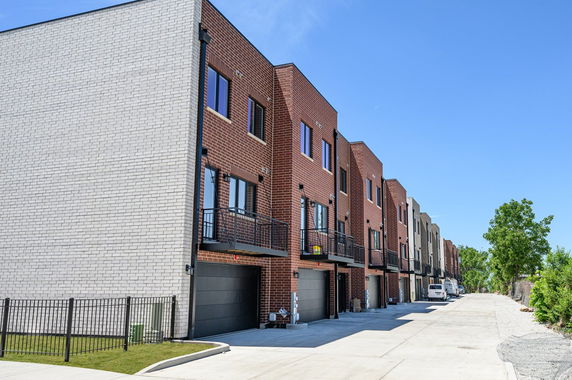 Front view of a row of modern townhouses with brick facades and garages.