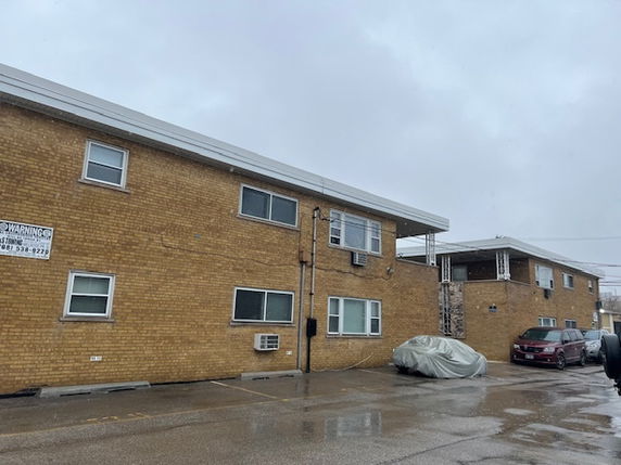 Front view of a two-story brick building with multiple windows and a parking area.