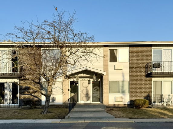 Front view of a two-story apartment building with a central entrance and large windows.