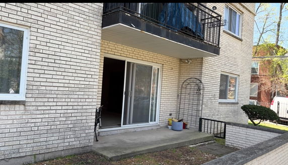 Front view of a brick multi-story building with a small patio and balcony.