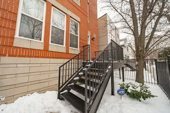 Front view of a building with red brick exterior and staircase entry.