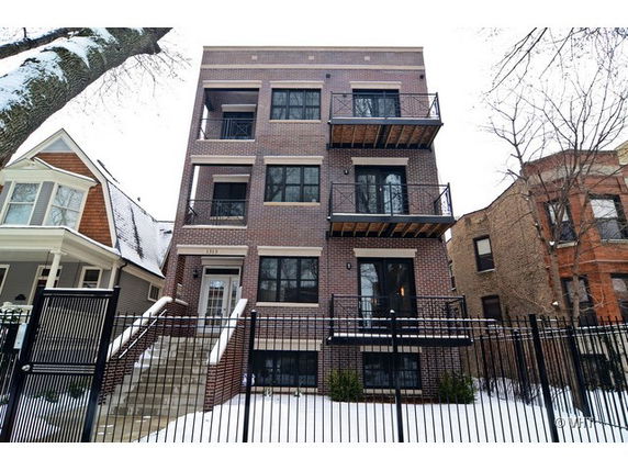 Front view of a multi-story brick apartment building with balconies.