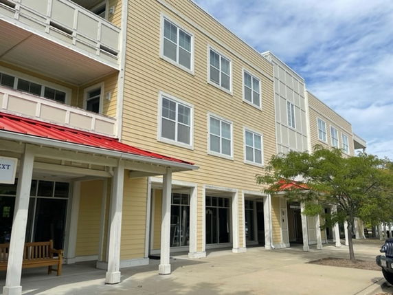 Front view of a multi-story building with a red roof and beige siding.