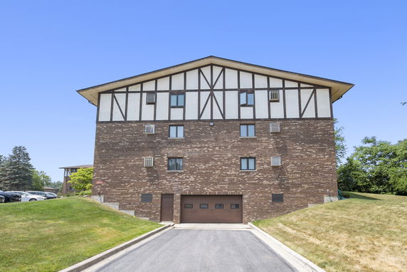 Front view of a multi-story brick building with a gabled roof and garage entrance.