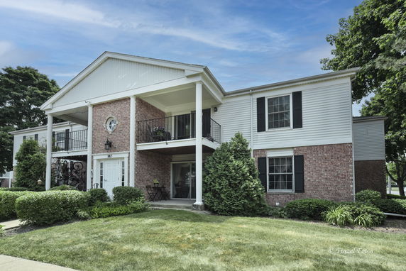 Front view of a two-story brick house with pillars and balconies.