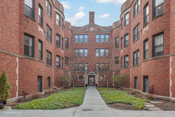 Front view of a multi-story brick apartment building with a central entrance.