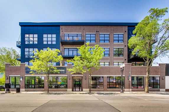 Front view of a modern four-story building with large windows and balconies.