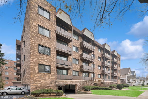 Front view of a multi-story brick apartment building with balconies.