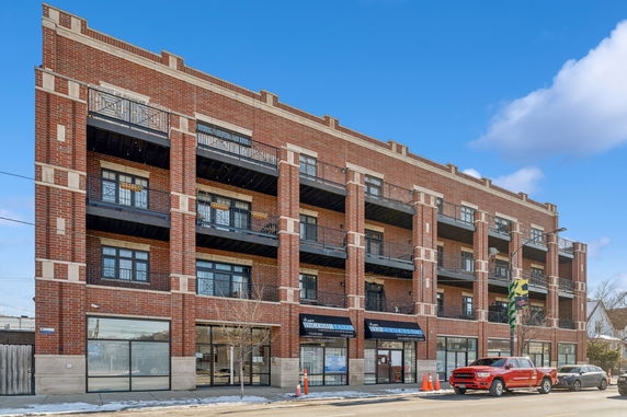 Front view of a three-story brick building with multiple balconies.