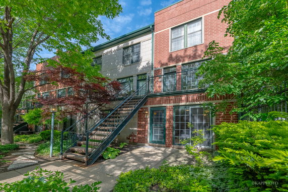 Front view of a multi-story brick building with exterior stairs and greenery.