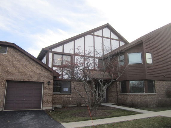 Front view of a two-story house with a garage and brick facade.