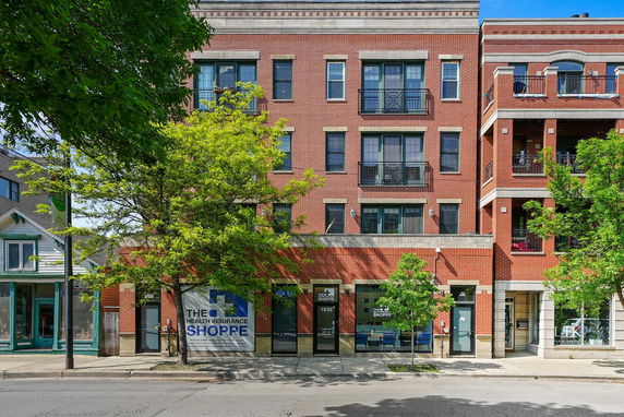 Front view of a red brick multi-story building with commercial spaces on the ground floor.