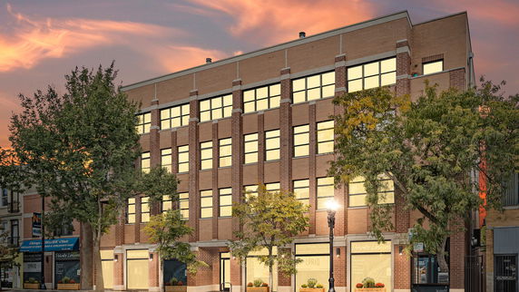 Front view of a multi-story brick building with large windows.