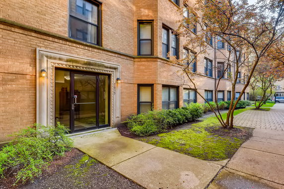 Front view of a multi-story brick apartment building with a glass entry door.