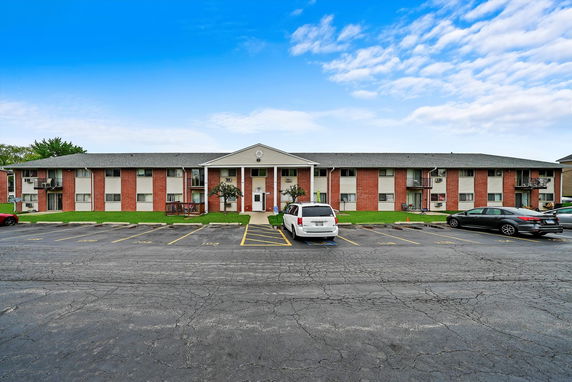 Front view of a two-story apartment building with a parking area.