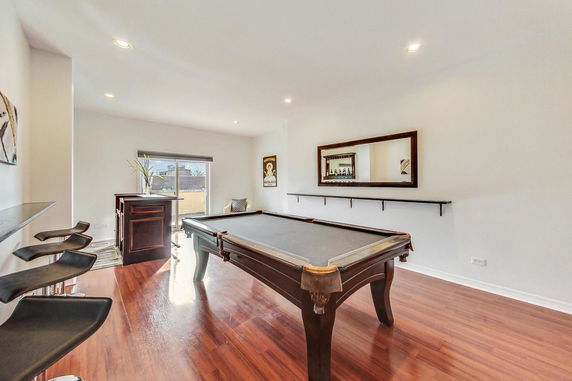 Room with a pool table and bar seating area.