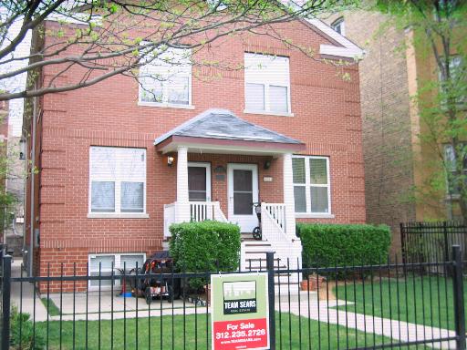 Front view of a two-story brick house with a small porch and white railing.