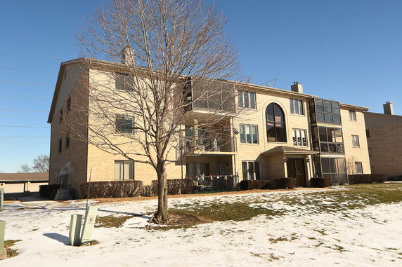 Front view of a three-story apartment building with balconies and large windows.