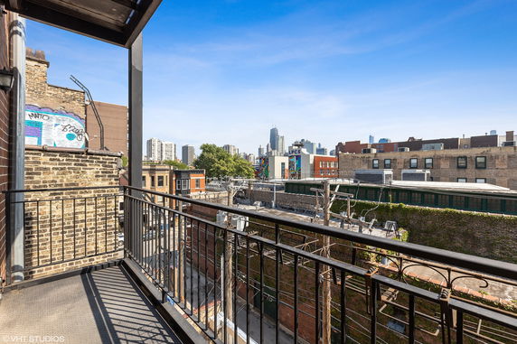 View from a balcony overlooking urban surroundings with city skyline in the distance.