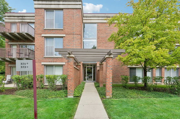 Front view of a brick apartment building with a covered entrance walkway.