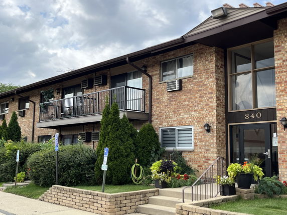 Front view of a two-story brick building with balconies and large windows.