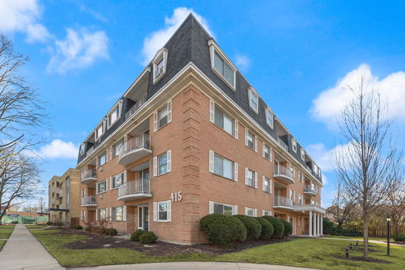 Front view of a multi-story brick apartment building with balconies.