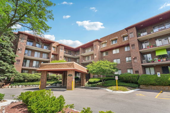 Front view of a multi-story brick apartment building with balconies.