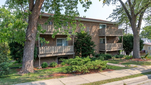 Front view of a multi-story brick residential building with balconies.