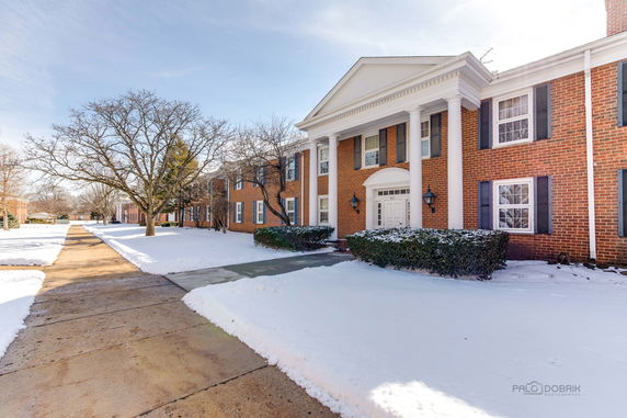 Front view of a two-story brick building with white columns and a snow-covered landscape.