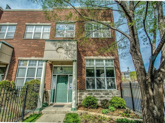 Front view of a two-story brick house with large windows and a green door.