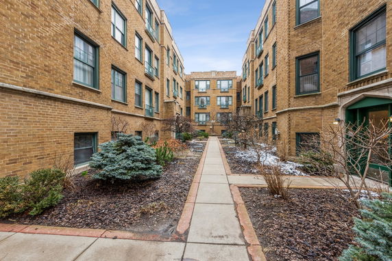 Front view of a brick apartment complex with three stories and multiple windows.