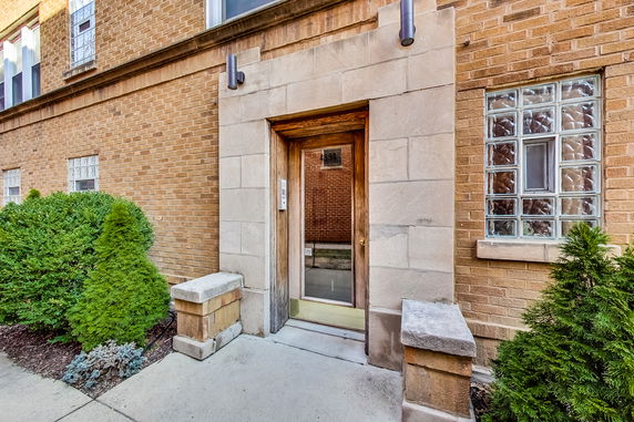 Front view of a brick building entrance with a glass door.