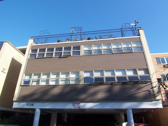 Front view of a multi-story building with a rooftop seating area.