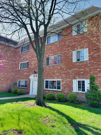 Front view of a multi-story brick building with white framed windows and a central entrance.