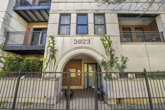 Front view of a multi-story building with balconies and an arched entrance.