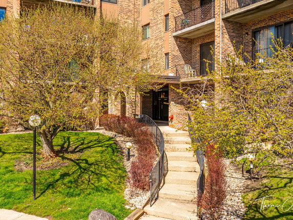 Front view of a multi-story brick building with balconies and a central entrance.