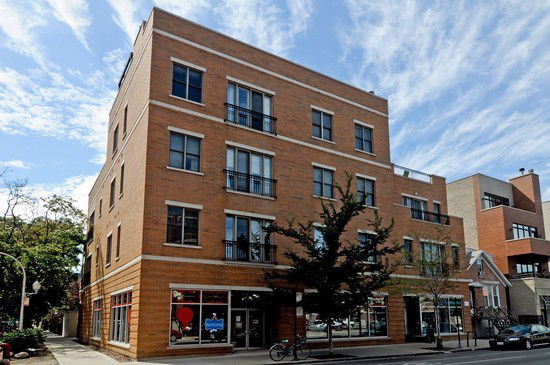 Front view of a multi-story brick building with large windows.