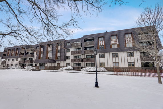 Front view of a multi-story residential building with balconies, set in a snowy environment.